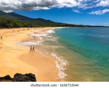Kihei, HI. USA. 09/30/2018: Perfect day at Big Beach (Makena Beach) on Maui. Swimmers run towards inviting waves.
