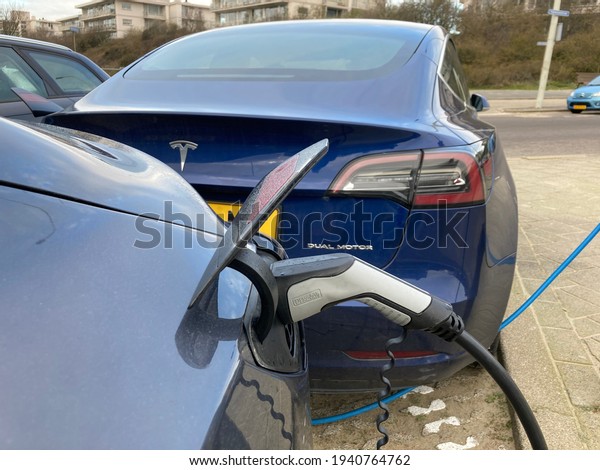 Kijkduin, the\
Netherlands - March 7 2021: Tesla electric car charging at plug in\
charge station in the\
Netherlands