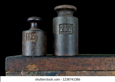 A kilogram weight used for weighing a given quantity in the store. Weights of one kilogram and two kilograms. Dark background.