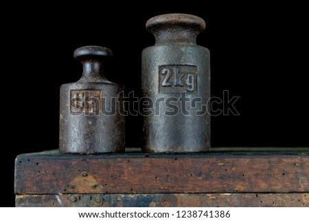 A kilogram weight used for weighing a given quantity in the store. Weights of one kilogram and two kilograms. Dark background.