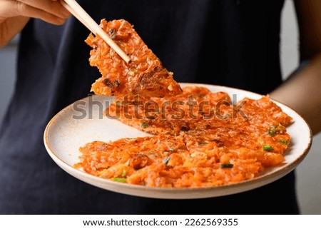 Kimchi pancake (Kimchi jeon or kimchi buchimgae) with hand ready to eating, Korean food
