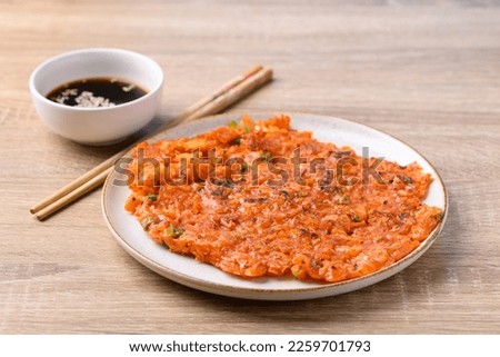 Kimchi pancake (Kimchi jeon or kimchi buchimgae) on plate eating with soy dipping sauce, Korean food