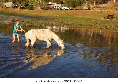 Kinchant Dam, Queensland, Australia - September 2015; Laughing Young Girl With A Stubborn Horse In The Water At The Edge Of A Camping Ground.                               