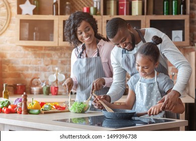 Kind african parents teaching their adorable daughter how to cook healthy food, free space - Powered by Shutterstock