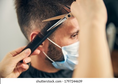 Kind bearded man looking forward, wearing mask while visiting salon in quarantine period - Powered by Shutterstock