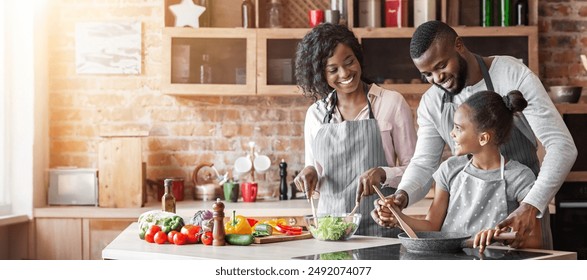 Kind black parents teaching their adorable daughter how to cook healthy food, kitchen interior, copy space - Powered by Shutterstock