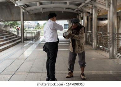 Kind Businessman giving money to old beggar or homeless guy at city walk in urban town. Poverty and social issue concept. Give and share with sympathy - Powered by Shutterstock