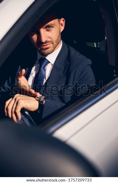 Kind businessman pointing at\
his new watches, being in his car while driving to business\
center