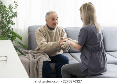 Kind female doctor embracing encouraging senior male patient in hospital. Happy healthy older man and his physician enjoying talking at nursing home. Elderly medical health care concept.