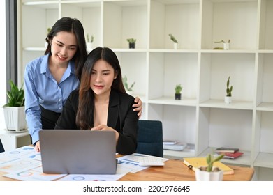 Kind And Happy Asian Female Boss Or Manager Supports Her Female Assistant By Giving A Hug during Work Together In The Office. Teamwork Concept