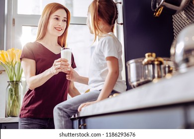 Kind Mom. Kind Loving Young Mother Gently Giving A Glass Of Milk To Her Daughter While Looking At Her And Smiling