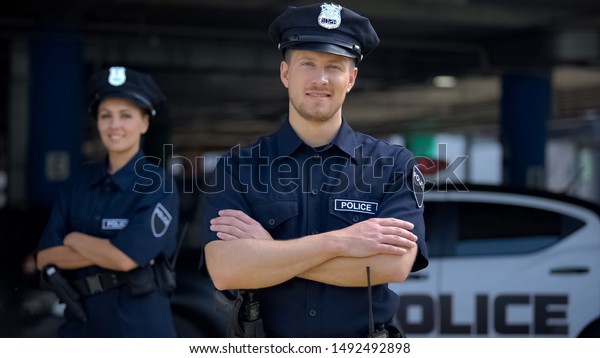 Kind police officers smiling standing near\
police station, ready to help,\
order