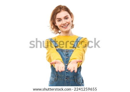 Kind red-haired girl giving empty hand to camera isolated on white background, cupped opens palms. Holding, showing, charity and poverty concept
