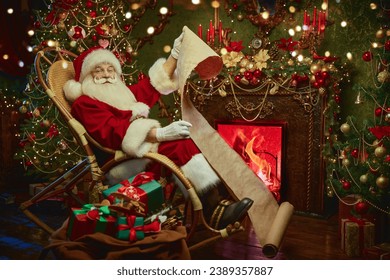 Kind Santa Claus sits in a rocking chair and reads an old scroll in a cozy Christmas room. Christmas and New Year. Festive preparations and gifts. - Powered by Shutterstock