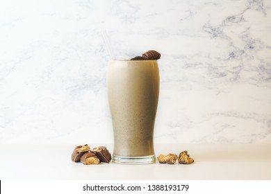 Kinder Bueno Milkshake Made With Ice Cream And Chocolate Candy Bar. In Tall Transparent Glass, Isolated. Decorated With Cookie Crumbs. On White Marble Background With Copy Space.