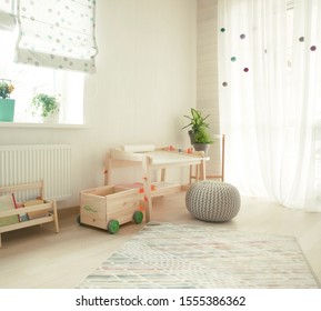 Kindergarten Apartment With Easel Chair And Table For Painting. Children Room Interior. Kids Room With Wooden Desk And Shelf With Books. White Sunny Room With Big Window For Young Child. Home Interior