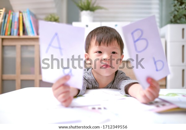 Kindergarten boy playing with flash cards , Asian\
children learning English with flash cards, Teach young kids\
English at home, Child at home, kindergarten closed during the\
Covid-19 health\
crisis