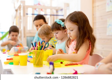 Kindergartenkinder, die Kunst und Kunsthandwerk mit Lehrer im Kindergartenzentrum