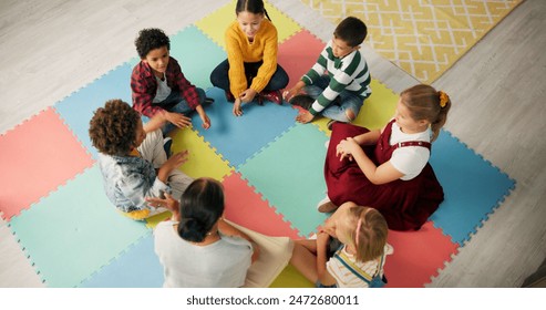 Kindergarten, children and hands with game in circle for development, growth and activity. Teacher, high angle and playful student on mat in class for sensory education, learning and creative skill - Powered by Shutterstock