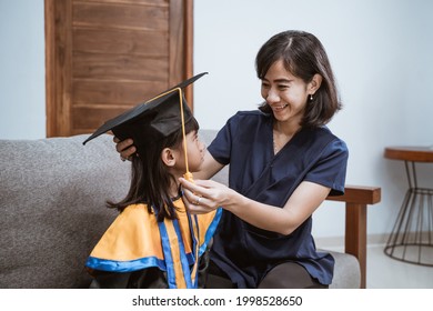 Kindergarten Graduation. Asian Mother And Kid Preparing On Her Kinder Graduate Day At Home