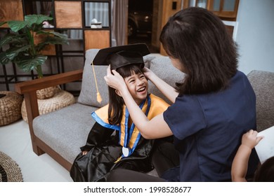 Kindergarten Graduation. Asian Mother And Kid Preparing On Her Kinder Graduate Day At Home