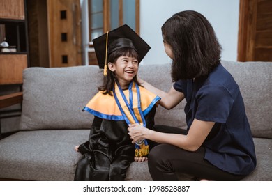 Kindergarten Graduation. Asian Mother And Kid Preparing On Her Kinder Graduate Day At Home