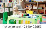 Kindergarten, table and empty classroom with paint for childhood development, art and crafts at school. Colorful, interior or equipment for drawing, creative lesson or mural activity at elementary