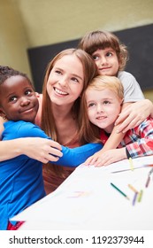 Kindergarten Teacher And Children Hug As Friends In The International Kindergarten