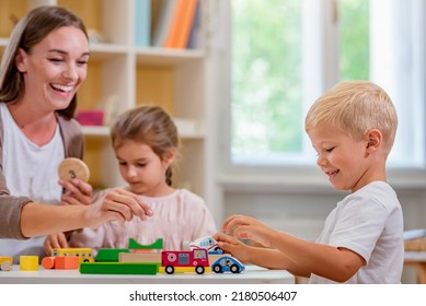 Kindergarten Teacher Playing Together With Children At Colorful Preschool Classroom. Mother Playing With Children.