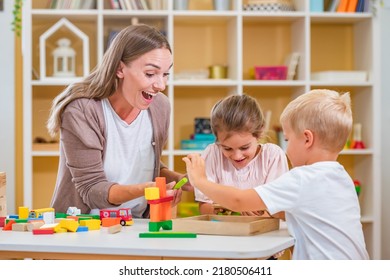 Kindergarten Teacher Playing Together With Children At Colorful Preschool Classroom. Mother Playing With Children.