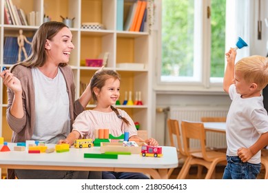 Kindergarten Teacher Playing Together With Children At Colorful Preschool Classroom. Mother Playing With Children.