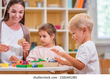 Kindergarten Teacher Playing Together With Children At Colorful Preschool Classroom. Mother Playing With Children.