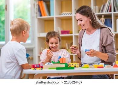 Kindergarten Teacher Playing Together With Children In The Colorful Preschool Classroom. Mother Playing With Children.