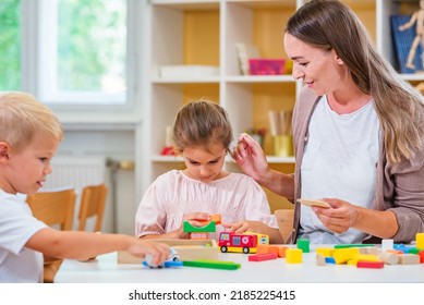 Kindergarten Teacher Playing Together With Children At Colorful Preschool Classroom. Mother Playing With Children.