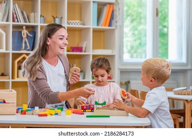 Kindergarten Teacher Playing Together With Children At Colorful Preschool Classroom. Mother Playing With Children.