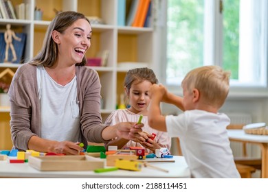 Kindergarten Teacher Playing Together With Children At Colorful Preschool Classroom. Mother Playing With Children.