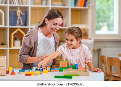 Kindergarten Teacher Playing Together With Children In The Colorful Preschool Classroom. Mother Playing With Children.
