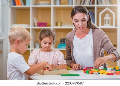 Kindergarten Teacher Playing Together With Children In The Colorful Preschool Classroom. Mother Playing With Children.
