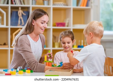 Kindergarten Teacher Playing Together With Children In The Colorful Preschool Classroom. Mother Playing With Children.
