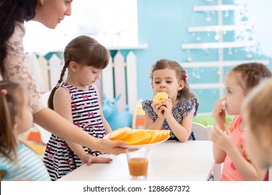 Kindergarten Teacher And Preschoolers Children Having Break For Fruits And Vegetables