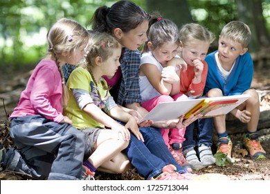 Kindergarten teacher reading with kids in a wood kindergarten - Shutterstock ID 1725713044
