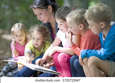 Kindergarten teacher reading with kids in a wood kindergarten - Shutterstock ID 1725713047