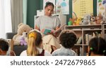 Kindergarten, teacher and reading a story to children in montessori school, classroom and learning. Kids, fairytale and woman teaching language in fantasy with creativity in preschool education