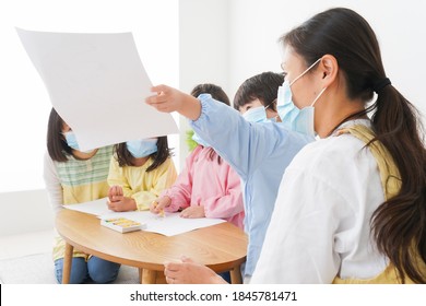 A Kindergartner And His Teacher Drawing With A Mask On