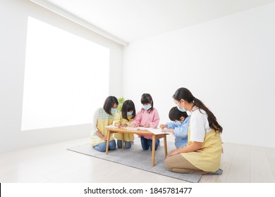 A Kindergartner And His Teacher Drawing With A Mask On