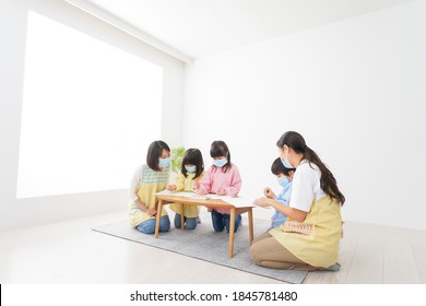 A Kindergartner And His Teacher Drawing With A Mask On