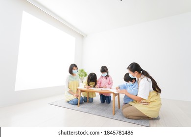 A Kindergartner And His Teacher Drawing With A Mask On