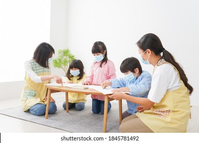 A Kindergartner And His Teacher Drawing With A Mask On