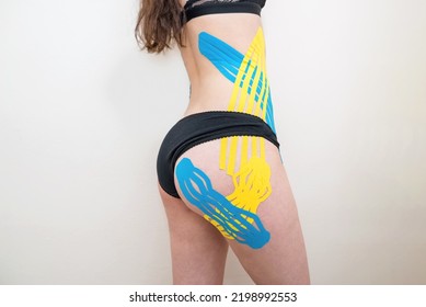 Kinesio taping, kinesiology. Kinesio taping on the body of a young girl. Sports girl with kinesio tapes on the buttocks and body on a white background.
