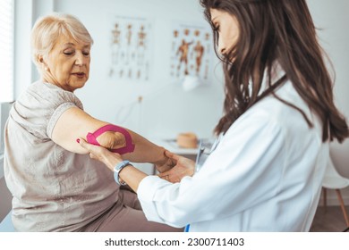 Kinesiology taping treatment with pink tape on senior patient injured arm. Woman hands apply kinesio treatment after muscle injury. A Modern rehabilitation physiotherapy worker with woman client - Powered by Shutterstock